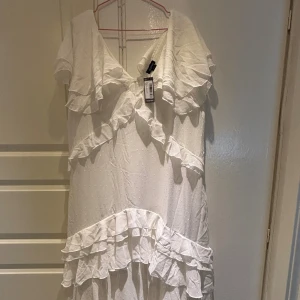 Vit volangklänning från Boohoo - Superfin lång vit klänning från Boohoo med v-ringning, volanger och korta ärmar. Säljer då klänningen är för stor för mig. Storlek 50/xxl