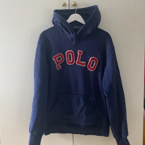 Mörkblå Polo Hoodie - Det är en mörkblå hoodie från Polo Ralph Lauren. Med ficka på magen och ett stort rött märke med texten ”POLO”. Vid fler frågor kom privat💯