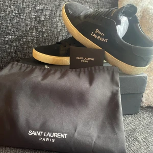 Svarta Saint Laurent sneakers - Säljer ett par riktigt schyssta saint Laurent skor för en bra peng för dig som vill ha ett par skor man kan ha när som helst👌 Säljs på grund av för lite användning och ligger och skräpar för jag har tröttnat på dem, OBS!!! På bild nmr 5 är de en liten defekt som ni kan se men skulle inte säga att de är något man tänker på och går säkert att lima ihop. Därav är priset ganska så lågt också⚡️😁