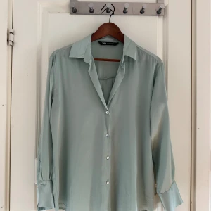 Ljusgrön satinblus från Zara - Snygg ljusgrön skjorta från Zara i satinliknande material. Den har tyvärr in kommit till användning. Storlek S men passar större då den är oversize i modellen!