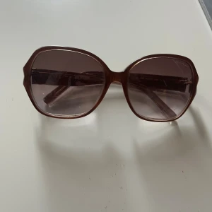 Bruna solglasögon Karl Lagerfeld - Stora, fyrkantiga solglasögon från Karl Lagerfeld i brun plast med tonade bruna glas. Snygg retrovibe och diskret logga på skalmen. Kommer med ett fodral från Karl Lagerfeld, kan skicka mer bilder på förfrågan!