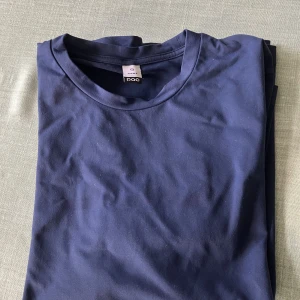 Mörkblå långärmad tröja från POC - En stilren mörkblå långärmad träningströja från POC i 92% nylon och 8% spandex. Tröjan har en klassisk rund halsringning och enkel design utan mönster eller detaljer.