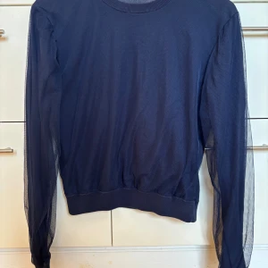 Mörkblå bomullströja med mesh från Acne Studios - Säljer en mörkblå bomullströja från Acne Studios  med rund halsringning. Tröjan har mörkblå mesh ovanpå bomullstyget som ger en cool effekt! Stilren med ribbade muddar i nederkant och vid ärmslut. Meshen ger en twist på en klassisk design. Storlek S, passar även XS.