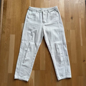 Snygga vita raka byxor med hög midja - Snygga vita byxor med raka ben och hög midja. Klassisk femficksmodell med bälteshällor och dragkedja. Byxorna har en clean look och passar fint till vardags.