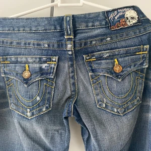 True Religion blå jeans med slitningar - Säljer ett par vintage jeans från true religion i storlek 26. Lappen finns kvar, alltså aldrig använda. Midjemåttet är 38 cm rakt över och innerbenslängden är 84 cm! Pris kan diskuteras