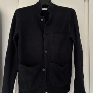 Blå ullkavaj från Selected Homme - Stilren Blå kavaj i ull från Selected Homme med tre stora utanpåfickor och knäppning framtill. Klassisk krage som kan bäras både uppvikt och nedvikt. Perfekt för dig som gillar en clean och tidlös look.