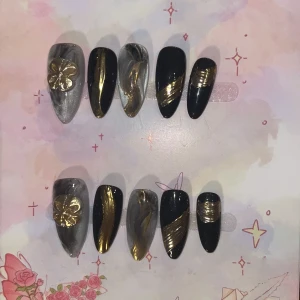 XS - Svarta och guldiga lösnaglar med marmor -  lösnaglar i svart och grå marmor med guldiga detaljer och 3D-blomma. Mandelform, perfekt för dig som vill sticka ut. 