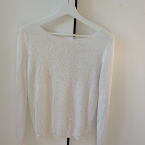Vit glittrig stickad tröja från Vila - Supersnygg vit stickad tröja från Vila med diskreta glittriga detaljer. Tröjan har rund halsringning och långa ärmar, perfekt för att lyfta din outfit med lite extra shine. Enkel och stilren modell som är lätt att matcha.