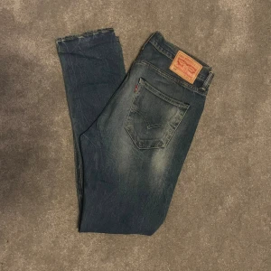 Levi's 520 blå jeans W32 L34 - Säljer ett par Levi's 520 jeans i klassisk blå tvätt med slitningar och snyggt blekta partier. Modellen har normal passform och raka ben. Ikonisk läderpatch bak och femficksdesign. Perfekta för dig som gillar en tidlös jeanslook. Pris kan diskuteras vid snabb affär!