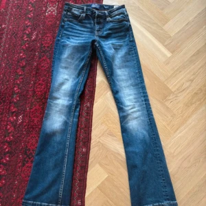 Crocker Pep! Bootcut jeans blå 26/31 - Snygga blå bootcut jeans från Crocker i modellen Pep! Boot. Jeansen har klassisk femficksdesign, normal midja och lätt slitna detaljer framtill och baktill. Materialet är jeans i bomull med lite stretch för skön passform.