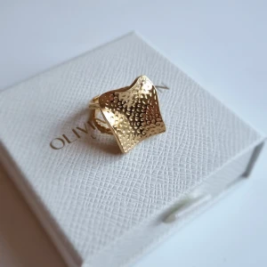 Guldfärgad ring  - Unik guldfärgad ring vågig, fyrkantig form och hamrad yta som ger cool textur. Ringen har en bred front och justerbar öppning baktill. Perfekt statement piece för dig som gillar att sticka ut med accessoarerna. Lådan ingår ej.
