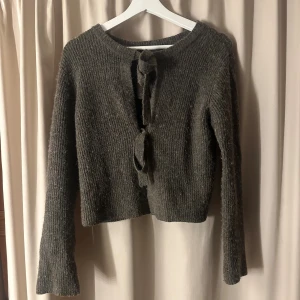 Mörkgrå stickad kofta med knyt - Mysig mörkgrå stickad kofta med långa ärmar och två knyt framtill. Lite använd, men blivit nopprig i tvätt💓