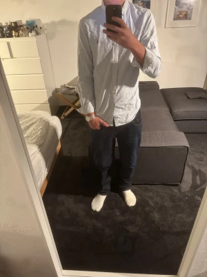 Randig skjorta från Polo Ralph Lauren - Säljer en klassisk blåvit randig skjorta från Polo Ralph Lauren i slim fit. Skjortan har button-down krage, långa ärmar och broderad logga på bröstet. Tillverkad i mjuk bomull och stängs med vita knappar framtill. Perfekt för en clean och stilren look.