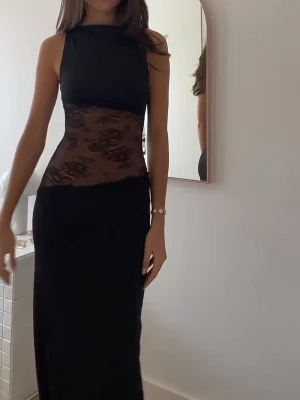 Svart långklänning med spetsdetaljer - Supersnygg svart långklänning från Peppermayo med  spets i midjan och öppen rygg. Använd endast en gång! Ord pris 1122kr. (2 första bilderna är inte mina)