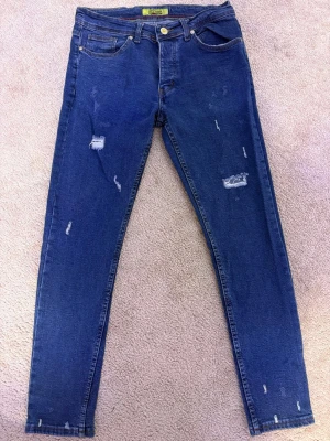 Tommy Hilfiger skinny jeans blå - Snygga blå skinny jeans från Tommy Hilfiger Denim med slitna detaljer och klassisk femficksdesign. Jeansen har normal midja och är tillverkade i stretchig denim för en tight passform. Perfekta för dig som gillar en trendig och avslappnad look.