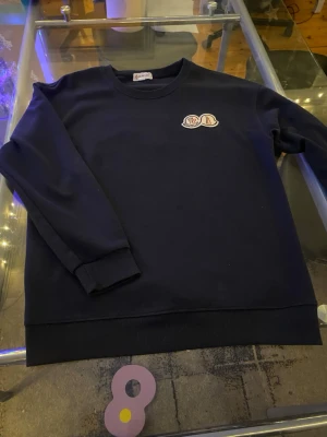 Moncler Sweatshirt - Snygg mörkblå sweatshirt från Moncler med broderad logga på bröstet och ärmen. Tröjan har rund hals, ribbade muddar och är långärmad. Perfekt för dig som gillar stilrena och exklusiva plagg med diskreta detaljer.
