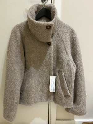  Ny slutsåld Beige  jacka med hög krage från arket i ull och alpacka Arket i ull och alpacka Stl 34    - Säljer en beige jacka  med fluffig yta och hög krage. Jackan har två stora knappar framtill, snedställda fickor och långa ärmar med knappdetalj vid mudden. Perfekt för dig som gillar mysiga och trendiga jackor med lite oversized känsla. Stl 34 slut såld , jag köpte för 2299kr passar  även till Stl S 