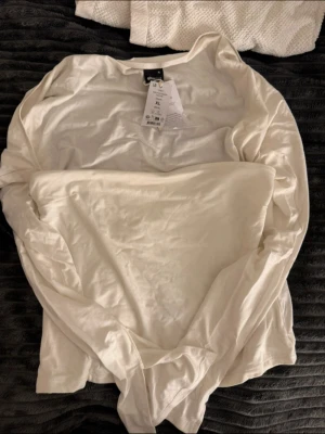 Vit långärmad topp från Gina Tricot - Säljer en enkel och stilren vit långärmad topp från Gina Tricot i storlek XL. Toppen är gjord i mjuk bomull och har en klassisk rund hals. Perfekt att matcha med jeans eller kjol för en clean look.