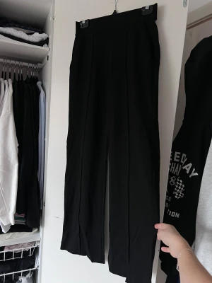 Svarta kostymbyxor från Cubus, storlek XS - Snygga svarta kostymbyxor med hög midja och raka ben. Byxorna har en stilren design med diskreta fickor baktill. Använda en gång! Önskar du veta exakta mått? Tveka inte att höra av dig!