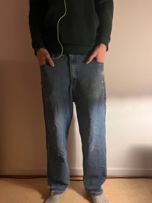  Yardsale loose fit jeans med brodyring - Blå jeans med röd kontrastsöm, loose fit och raka ben. Snygg broderad detalj på bakfickan och broderad logga vid fickan. Klassisk femficksmodell i jeansmaterial, perfekt för dig som gillar streetwear-vibe.
