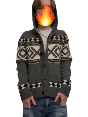 Grå stickad hoodie-kofta med mönster - Snygg grå stickad kofta med huva från Urban Classics. Tröjan har vita och svarta geometriska mönster, knappar framtill och ribbade muddar. Perfekt för dig som gillar chill och stilren look med lite extra detaljer. Storlek L passar M/S (BVSA!!!)