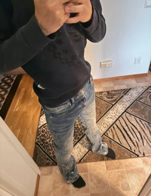 Amiri jeans - Säljer ett par blåa flared jeans från Amiri med coola slitningar och vita färgstänk längs benen. Jeansen har klassisk femficksdesign, dragkedja och knapp i midjan. Materialet är jeans med snygg tvättad look och detaljer som ger en unik vibe.