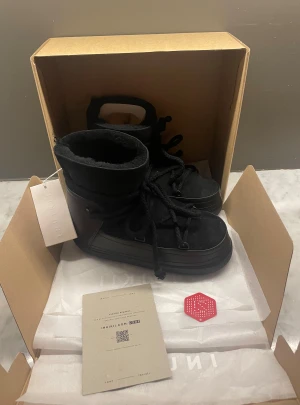 Svarta Inuikii skor - Svarta boots från Inuikii med snörning och rund tå. Utsidan är i mocka och skinn, insidan är fodrad med mjuk päls för extra värme. Perfekt för kalla dagar nu i vinter. Skorna är aldrig rörda! Nypris runt 3000. OG medföljer (se på bild 5) skorna har även QR-kod (se på bild 6)                                Skriv vid frågor, priset är inte hugget i sten!🤝