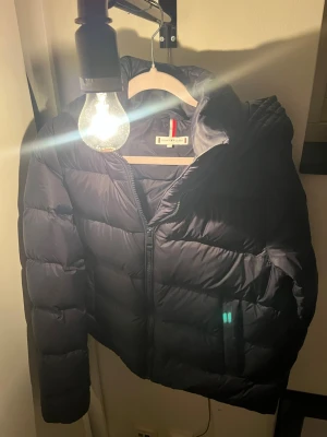 Tommy Hilfiger vinterjacka - Jackan är knappt använd men har en slitning som lagats med en lapp på höger ficka. Skulle inte påstå att man ser den. 