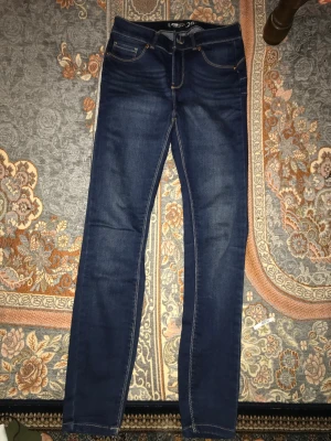 Mörkblå skinny push up jeans FB Sister - Snygga mörkblå skinny push up jeans från FB Sister i storlek W26. Jeansen har klassisk femficksdesign, kontrastsömmar och smal passform som sitter tight hela vägen ner. Perfekta för dig som gillar en slimmad look och vill framhäva benen.