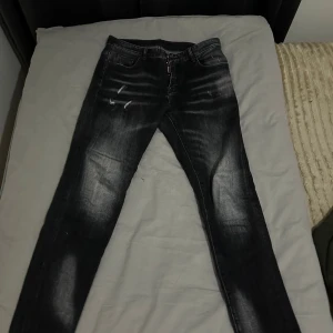 Svarta jeans med tryck dsq - Snygga svarta jeans med slitningar och blekta detaljer, Perfekta för dig som gillar streetstyle och vill sticka ut lite extra.