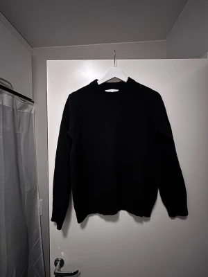 Svart stickad tröja från Samsøe Samsøe - Svart stickad tröja från Samsøe Samsøe med rund hals och ribbade muddar. Klassisk och enkel design med långärmade ärmar, perfekt för lager-på-lager under kyliga dagar. Mjuk och skön känsla, passar till jeans eller chinos.