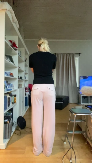 Ljusrosa mjukisbyxor med snörning - Säljer ett par ljusrosa mjukisbyxor från jucie couture med bred resår och snörning i midjan. Byxorna har raka ben, fickor fram och bak med knappdetaljer. Perfekta för chill dagar och har en loose passform som ger skön vibe.