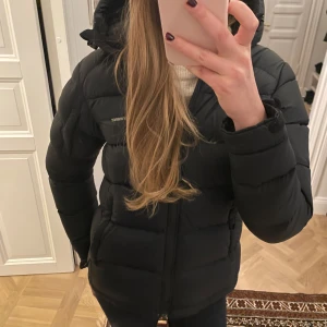 Mörkblå dunjacka!!!❤️ - Mörkblå  Peak Performance dun jacka i perfekt kombo av varm dunjacka/skidjacka i storlek XS! Smidig luva och diskret ficka för liftkort på ärmen! Samt inner fikor och fikor med dragkedja på sidorna.  Perfekt för kalla dagar och riktigt snygg till streetwear-stilen.❄️