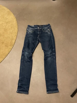 Replay Anbass slim  mörkblå jeans - Snygga mörkblå Replay Anbass jeans med klassisk femficksdesign slim. Jeansen har diskreta slitningar och kontrastsömmar, vilket ger en cool och modern look. Passar dig som gillar stilrena och tidlösa jeans med bra passform.