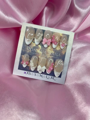 SweetFrench (XS);Medium Almond - Säljer ett set press-on naglar i almondform med handmålade franska tippar, dekorerade med 3D rosetter, pärlor och blommor i vitt och rosa. Naglarna har en nude bas och detaljer som hjärtan och pärlsträngar för en extra söt look. Perfekt för dig som vill ha unika och kreativa naglar.XS: 14 mm, 11 mm, 11,5 mm, 10 mm, 8 mm  