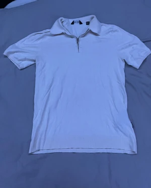 Vit pikétröja med dragkedja Only & Sons - Fräsch vit pikétröja från Only & Sons i storlek S. Tröjan har klassisk krage, korta ärmar och en snygg dragkedja framtill. Materialet är mjuk bomull och nederkanten är ribbad för extra stil. Perfekt för dig som gillar clean och enkel look.