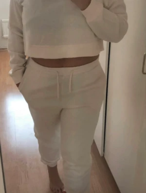 SET! Mjukisbyxa med hoodie från H&M - Säljer en crèmefärgad croppad sweatshirt med hög krage och långa ärmar samt med tillhörande mjukisbyxor med elastisk midja och snörning. Setet har en relax fit som passar perfekt till chill dagar. Enkel och stilren design utan tryck eller mönster. TRÖJAN ÄR I STORLEK M OCH BYXAN I STORLEK XS