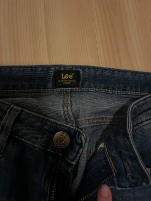 Bootcut jeans från Lee W28 L31 - Snygga blå bootcut jeans från Lee i klassisk modell. Men detaljer på fickorna. Är lite söndriga där nere. Är 170 och dom är lite långa 