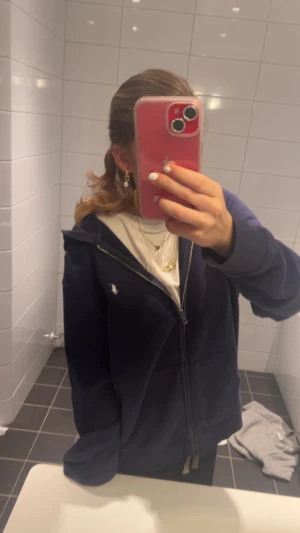 Marinblå hoodie från Ralph Lauren - Säljer en marinblå hoodie från Ralph Lauren med dragkedja och huva. Är i jätte bra skick och inte alls så använd. Nypris 1200. Är i ungdomsstorlek XL de står 18-20 men jag har XS-S och ni ser hur den sitter på mig😊 