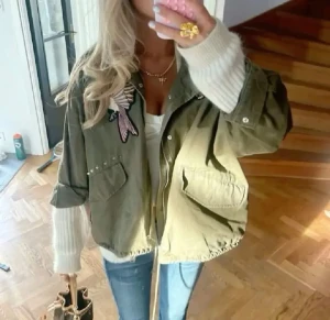 Olivgrön overshirt med broderier - Säljer en olivgrön overshirt med coola broderade detaljer som fågel och rosor på bröstet och ärmen. Jackan har knappar framtill, två stora fickor och en loose passform. Perfekt för dig som gillar statement-plagg och vill sticka ut lite extra.