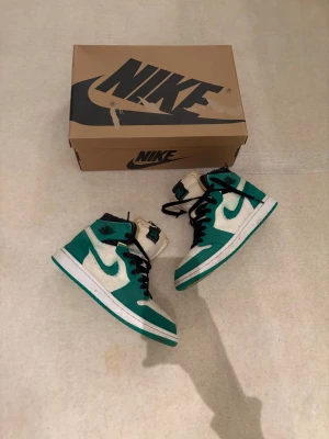 Nike Air Jordan 1 Zoom gröna sneakers - Nike Air Jordan 1 Zoom sneakers i en fräsch grön och vit färg med svarta snören och detaljer. Höga med rund tå och platt sula, tillverkade i mocka och syntet. Sulan är limegrön undertill och skorna har klassisk Zoom Air-tagg på plösen. Box medföljer. Storlek 40. Kan göra en bra deal på dessa skor då jag bara vill bli av med dom. Skickar samma dag som köp! 