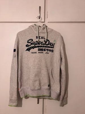 Ljusgrå Superdry hoodie med tryck - Snygg grå hoodie från Superdry Perfekt för kalla dagar men även lite lugnare dagar 