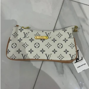  kuvertväska - Snygg vit kuvertväska. Kanterna är i ljusbrunt skinn och materialet känns lyxigt och slitstarkt.