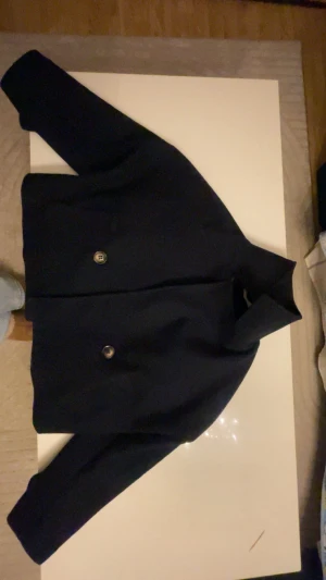 Svart Kappa från Missay - Svart kappa från Missat, tillverkad i 66% polyester med slät yta och fodrad insida. Kappan har en unik form med bred linning och dekorativa knappar. Perfekt för dig som gillar stilrena och moderna plagg. Vet ej vad de är för storlek då de ej står men jag bär vanligtvis S men det hade nog passat någon med XS, pris kan alltid diskuteras vid snabb affär!💕