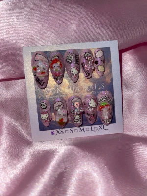 PinkKitty(XS);Medium Almond - Supergulliga handgjorda press-on naglar i rosa med glitter, dekorerade med Hello Kitty, björnar och söta HK 3D-figurer med jordgubbar, moln och text. Naglarna har en medium mandelform och kommer i XS: 14 mm, 11 mm, 11,5 mm, 10 mm, 8 mm. Perfekt för dig som älskar kawaii och detaljerade motiv.