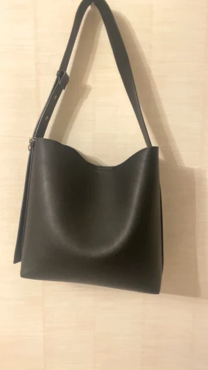 Svart axelväska i skinn - Stilren svart axelväska med justerbar rem och minimalistisk design. Medkommer en necessär också! 🫶