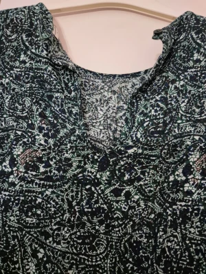 Klänning - Snygg klänning från Jacqueline de Yong i storlek 38. Klänningen har ett blått och vitt mönster, v-ringad hals och långa ärmar. Materialet är mjukt och lätt, perfekt för dig som gillar en chill och stilren look med lite edge.