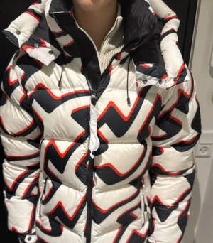 Vit pufferjacka från J.Lindeberg - Säljer denna J.lindeberg jacka med coolt mönster pga att den va för stor. Den är helt ny med tags och alla medhavande tillbehör. En incident som uppstod när jag skulle öppna jackan så råka jag göra en reva i den. Så det finns en lagning på ryggen men utöver det är den helt ny. Ny pris ca 3000kr.