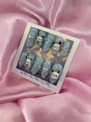 CuteP (XS);Medium Almond - Supergulliga press-on naglar i glittrigt ljusblått med sanrio detaljer i 3D-motiv av söta hundar och hjärtan. Naglarna är spetsiga och har handmålade 3D dekorationer med små pärlor och figurer. Perfekt för dig som vill ha unika och lekfulla naglar.XS: 14 mm, 11 mm, 11,5 mm, 10 mm, 8 mm 