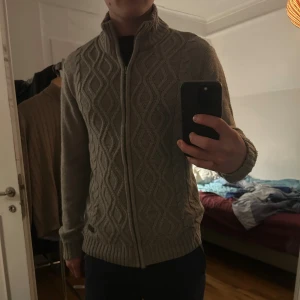 Kabelstickad ziptröja - Säljer en väldigt snygg och varm tröja av ett något okänt märke. Inga defekter och väldigt skön. Han jag köpte den av här på Plick verkade inte vara nåt större fan av storlekar för den lappen tyckte han var smart att klippa bort. Men jag själv är 182 och väger 80 kg så storleken är väll runt M/L någonstans. Kan endast skicka under helgerna men är snabb på att svara när det kommer till seriösa frågor. MVH//Nisse